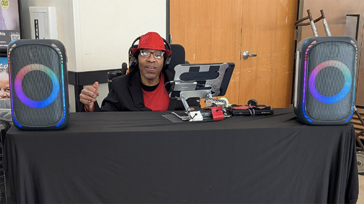 Black man in a wheelchair behind a desk with a computer on it