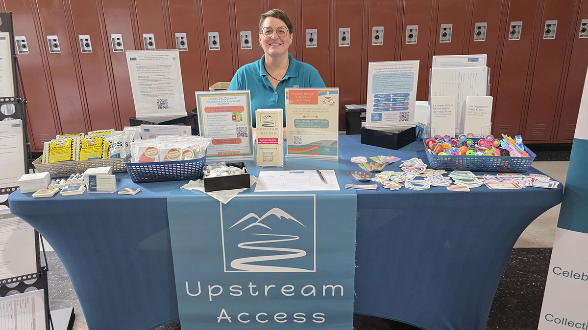 Erin sitting behind a table with resources on it at a tabling event.