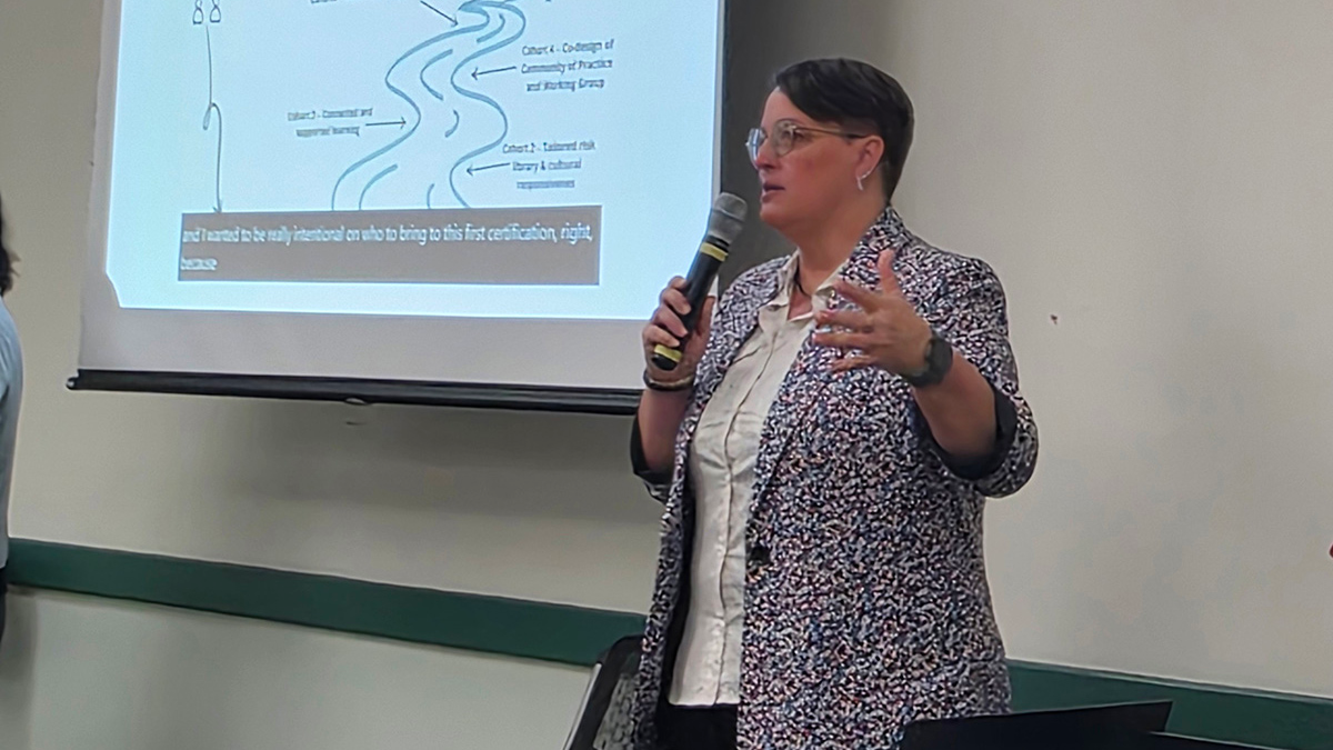 Erin Taylor giving a presentation in front of a screen with a projected slide