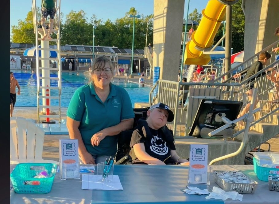 Jenni and Gabe at neurodiversity fair with a pool behind them.